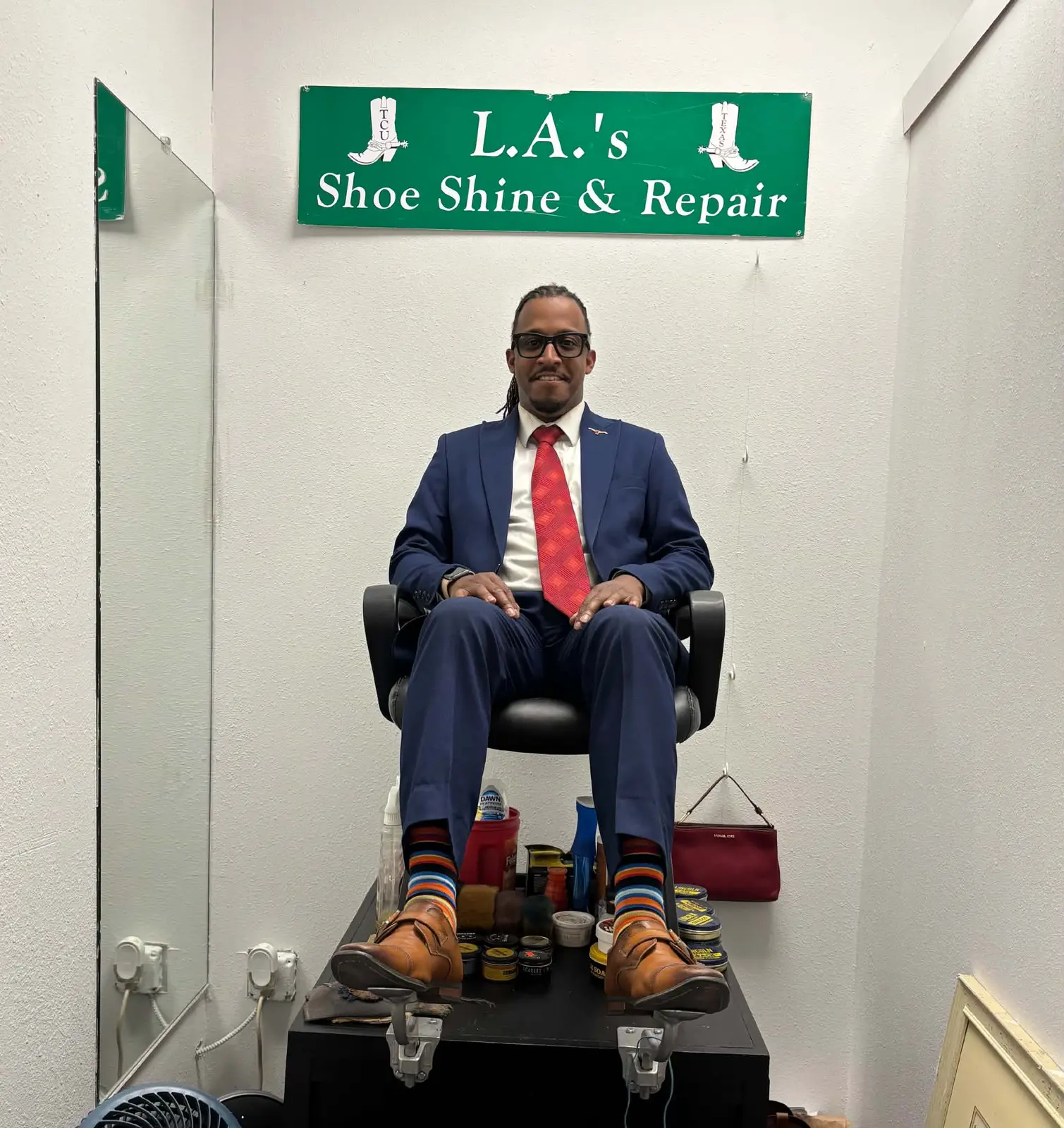 Customer seated beneath the L.A.'s Shoe Shine and Repair sign